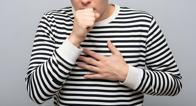 Close-up of adult coughing with hand on chest in striped shirt, Person covering mouth while experiencing chest discomfort, Studio shot showing cough or breathing difficulty concept, Health and illness