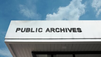A Public Archives word sign displayed on a civic or government building under a clear blue sky, symbolizing historical records, official documents, heritage, research, and institutional memory