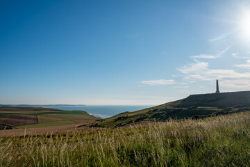Cap Blanc-Nez, Escalles, Pas-de-Calais, Hauts-de-France, France, July 29th, 2025, Enjoy a breathtaking scenic view of coastal hills and a remarkable monument set against a vibrant bright blue sky