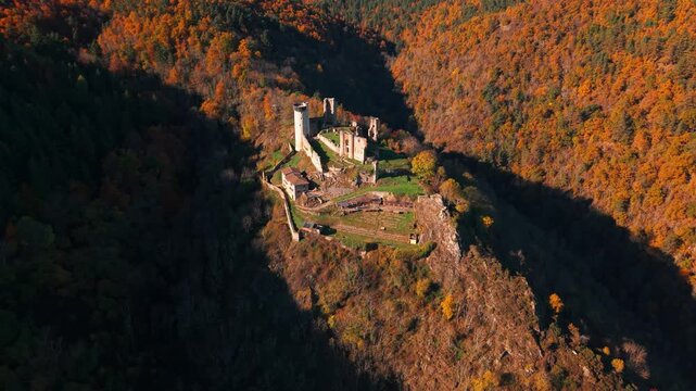 Aerial shot flying away from the Rochebaron Castle near Bas En Basset, revealing the landscape during fall season, Haute Loire departement, Auvergne Rhone Alpes region, France