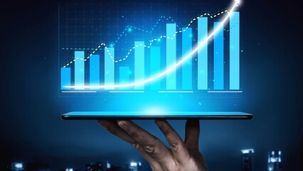 A hand holds a tablet displaying a vibrant financial graph, symbolizing business growth and...