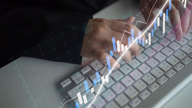Focused hands typing on a keyboard with overlayed digital graph elements showcasing market trends and financial growth for professional analysis. Copula - Powered by Adobe