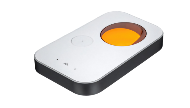 Angled, silver electronic device with orange circular recessed area on a black background, top view