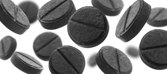 Black activated carbon tablets levitate on a white background