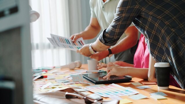 Close up of project manager working together brainstorming idea while looking at color palettes while businessman design logo graphic. Professional business team choosing color together. Symposium.
