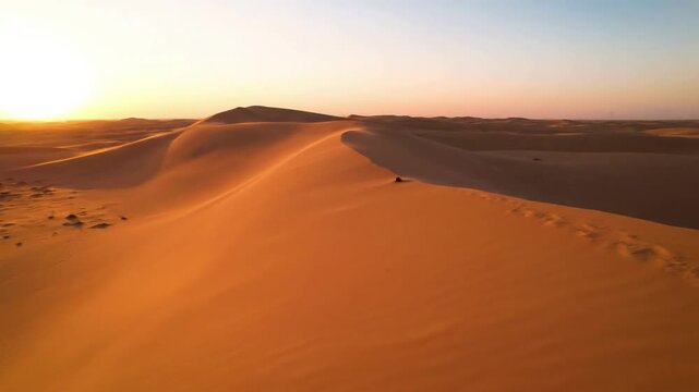 Dynamic time lapse of shadows lengthening across a series of sand dunes as the sun sets, revealing changing colors and emphasizing the desert's shifting forms.