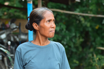 The same mother glances off-camera with a thoughtful, pensive look as she stands near her rural...