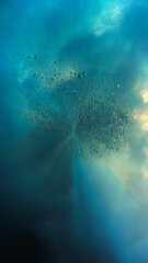 Floating beneath the wild ocean surface. Underwater photography. Below the wild surface- Rays of light through the waves. 