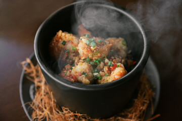 Hot Stir-Fried Seafood Served in Black Bowl with Steam Rising