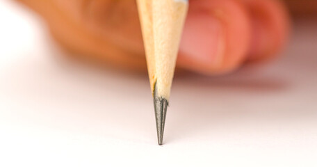 Pencil is being used to write on a white surface pencil is sharpened and has pointy tip, Concept of...