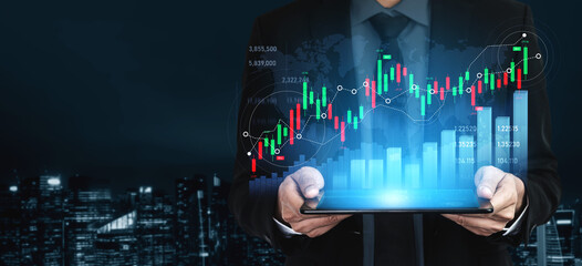 A businessman analyzes digital graphs on a tablet, illustrating financial trends and growth in a modern urban landscape during the night. Scalp