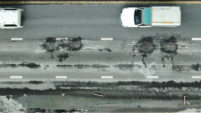 Visible deterioration in this top-down road photo signals infrastructure neglect, risk to motorists, higher repair costs, inadequate investment, pollution from debris, and city planning issues.
