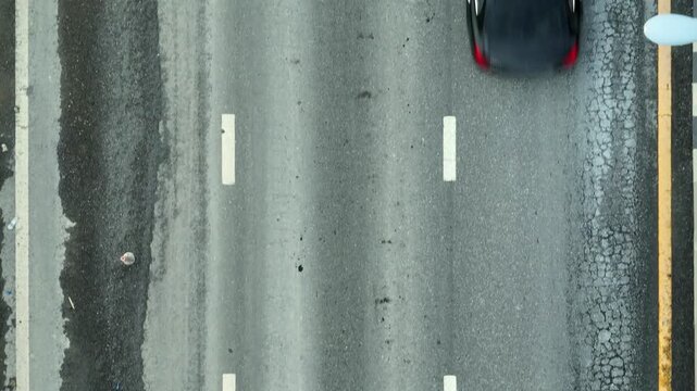 Drone imagery shows an asphalt road in disrepair, symbolizing infrastructure neglect, risk to motorists, lack of resources, city management flaws, environmental exposure, and the call for action.
