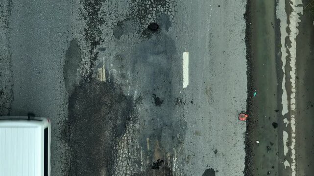 Aerial drone view of severely damaged asphalt highlights infrastructure decay, neglected maintenance, safety hazards, public investment gaps, environmental risk, and urgent repair needs.

