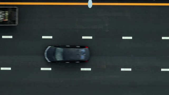 New asphalt road with a moving vehicle seen from above, representing modern infrastructure, improved safety, and regional connectivity that supports economic opportunities, transportation efficiency.
