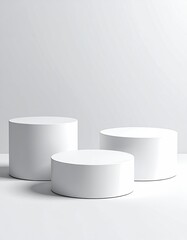 Three white cylinder podiums on white backdrop