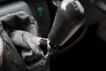 Close up view of worn, torn, and damaged car gear stick inside an old vehicle interior. broken lever and obsolete gaiter show clear signs of neglect and decay
