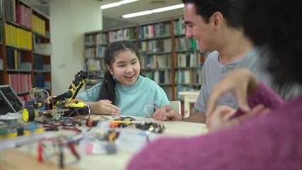 A teacher guiding students in a robotics project during a STEM class in the library - Powered by Adobe