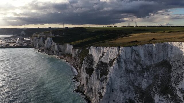 Port of Dover, The UK, industrial harbor for ferries from abbroad. Aerial drone video of the limestone cliffs and port at sunset.
