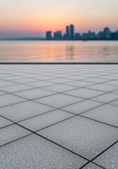 Empty urban waterfront promenade with frosty tiles overlooking tranquil city skyline at sunrise and calm reflective water