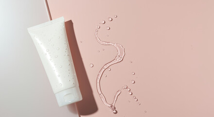 Obraz premium Moisturizing cream tube with water droplets on minimal pink background emphasizing hydration and clean skincare concept