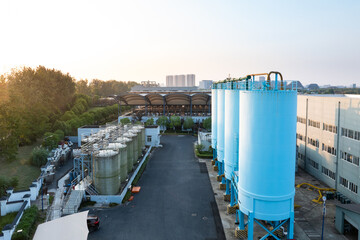 Aerial view of industrial tanks with pipes, by building