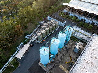 Aerial view of industrial tanks with pipes, by building