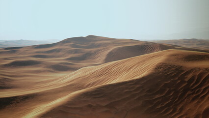 Waves of golden sand rise and fall across an expansive desert, glowing under a clear blue sky. The tranquil landscape invites a sense of calm and adventure, showcasing natures beauty.