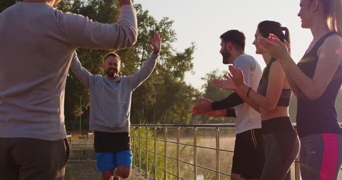 Sporty happy man winner running approaching group of friends clapping enthusiastically, encouragement in outdoor supportive and celebratory team jog, feeling shared accomplishment of fitness  - Powered by Adobe
