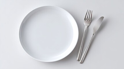 Empty White Plate with Silver Knife and Fork on Clean Surface for Minimalist Dining or Culinary Presentation