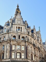 Fototapeta premium Ornate historic building facade in Antwerp, Belgium featuring detailed architecture and intricate sculptures under a clear sky
