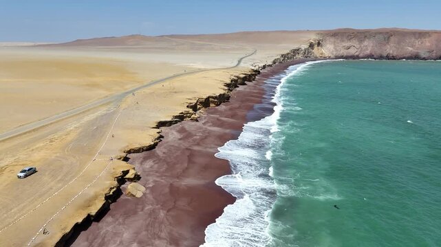 Flying along the unique red sand beach of Playa Roja in Peru's Paracas National Reserve, showcasing the dramatic desert coastline