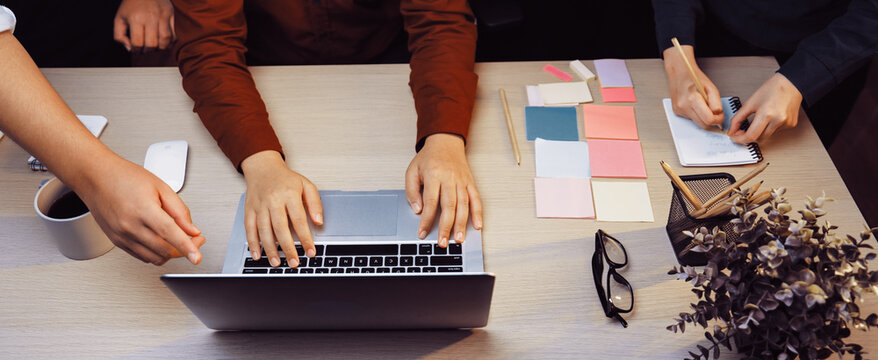 A dynamic workspace featuring a laptop and vibrant sticky notes, highlighting hands of individuals collaborating in a creative brainstorming session. SACTR - Powered by Adobe