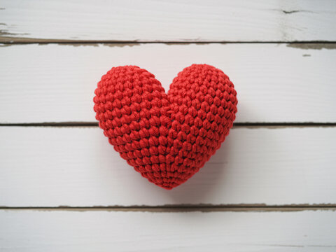 Express your love with this charming hand-knitted red heart prop on rustic white wood, perfect for Valentine's Day campaigns and heartfelt designs - Powered by Adobe