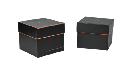 Two black square boxes with thin copper bands accenting edges, slightly offset, on black backdrop. Minimalist, elegant