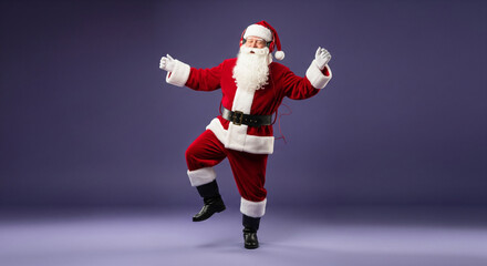 Joyful Santa Claus in a traditional red suit and white beard dancing happily against a solid purple studio background for the Christmas holiday
