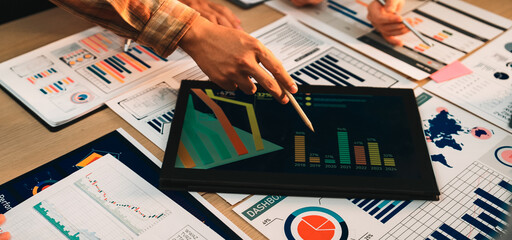 A diverse business team engages in collaborative data analysis using charts and graphs displayed on...