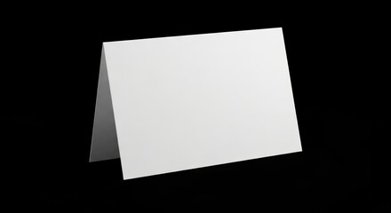 A white blank card stands on a reflective black surface