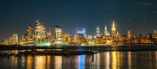 Fototapeta premium The Manhattan skyline in night New York city at dusk. Iconic city view of New York in night. NY night towers above the Hudson. Famous New York panorama. Classic New York cityscape panoramic view.