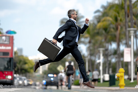 Busy rich businessman running to a meeting. Businessman run on road. Business man in a suit run to work. Business man jump and run outdoor. Businessman running to meet. Business man run in hurry.