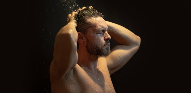 40s man taking a shower and washing his face with soap. Mature male in the bath. Guy applying shampoo and foam to his hair in the bathroom. Man washing body and face in a modern bathtub. - Powered by Adobe