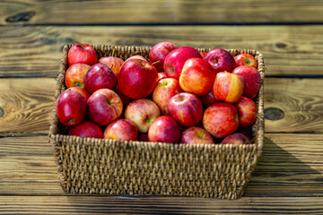 Fresh red apples in basket on wooden table. Harvest with fresh red apples. Basket full of fresh apples.