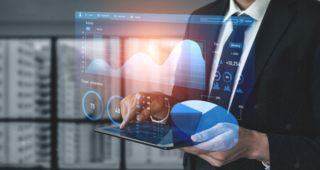 A businessman in a suit engages with a digital tablet, analyzing data trends through interactive infographics in a contemporary office setting. Impute