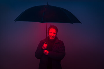 Mature Man Poses With Umbrella in Studio Surrounded by 80s Retro Neon Lights