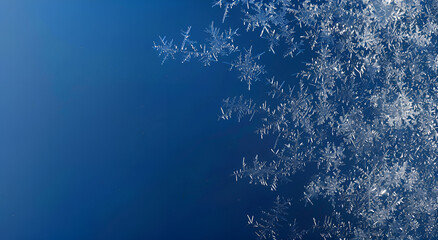 Zbliżenie na śnieżynki na szkle z ciemnoniebieskim tłem – zimowa tekstura, mróz i delikatność natury.