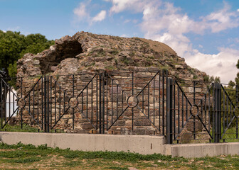 Ruins of Castle Masjid, in Kadifekale Castle, Izmir, Turkey. Ancient stone mosque remains, partially overgrown, behind a protective fence under a cloudy sky.