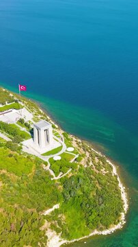 Vertical video. Eceabat, Turkey. Dardanelles Strait, coastline, Canakkale Martyrs Memorial, Turkish flag, Hisarlik Hill, clear day, drone. Aerial View, Dronie, Spiral backward. Rich colors