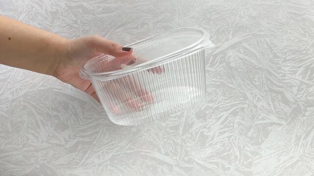 Plastic disposable transparent container in women's hands. Utensils for takeaway food.