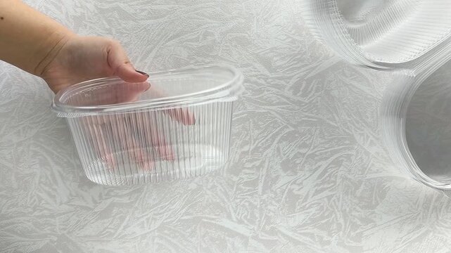 Plastic disposable transparent container in women's hands. Utensils for takeaway food.