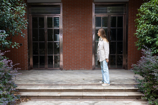 Young woman standing in front of a brick building with glass doors